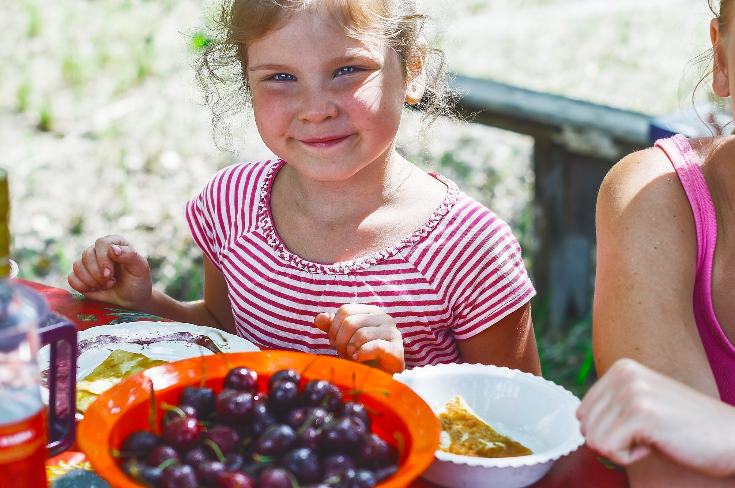 Smiling girl at picnic table with bowl of grapes in front of her