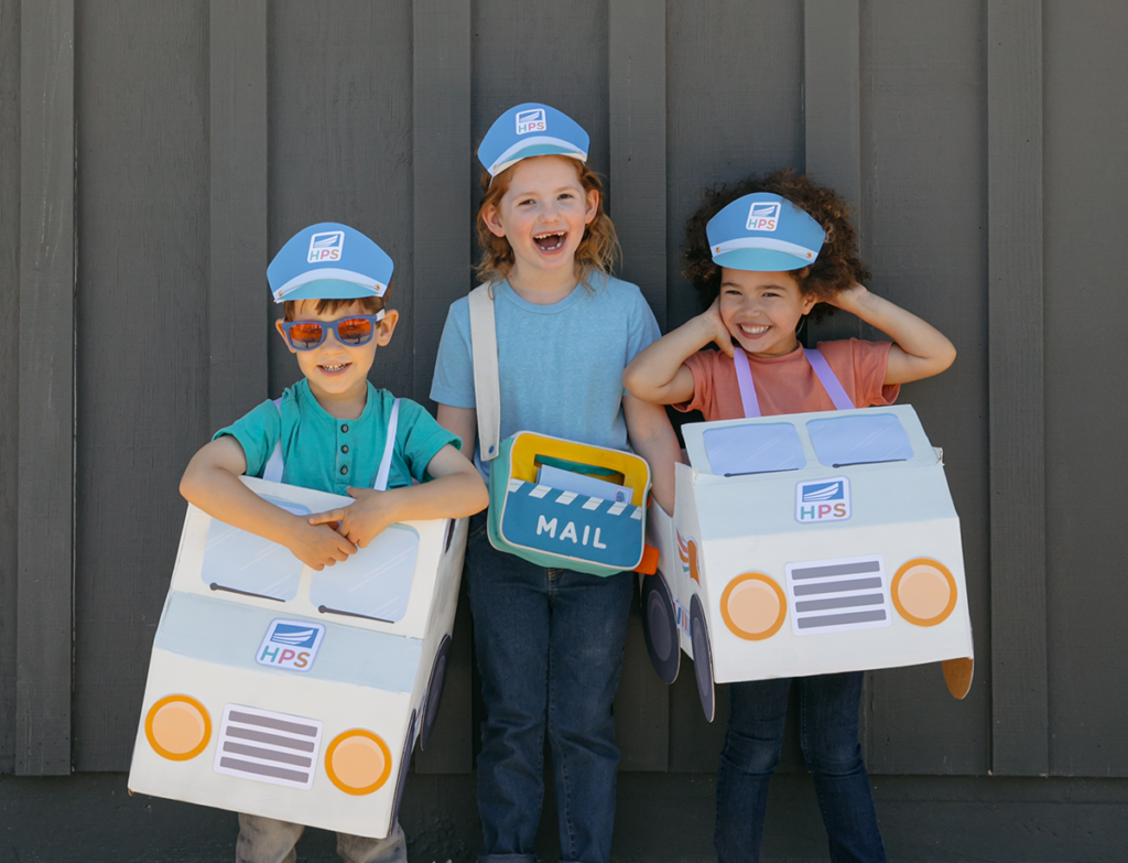 Three kids playing with finished printable DIY mail trucks
