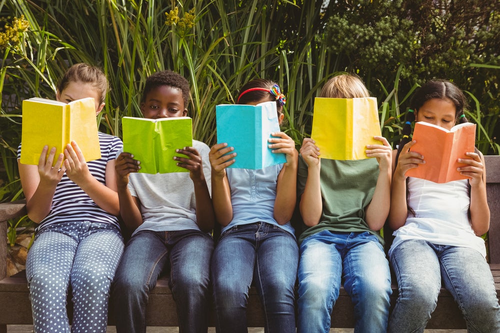 Five kids sitting outside reading books