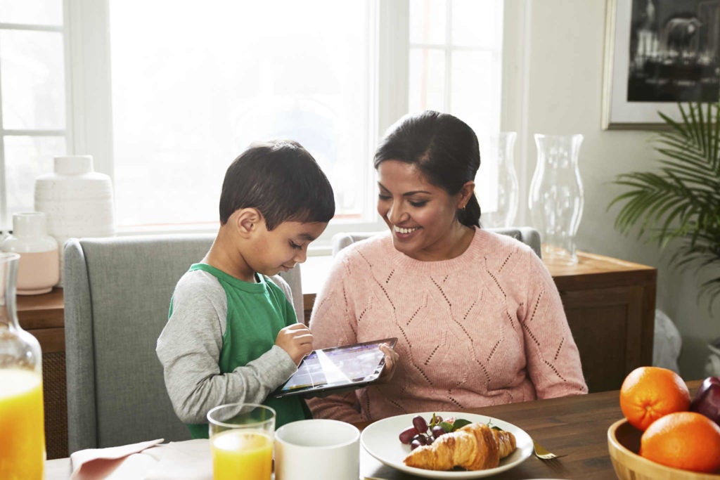 Mother and child using reading app on tablet at breakfast table