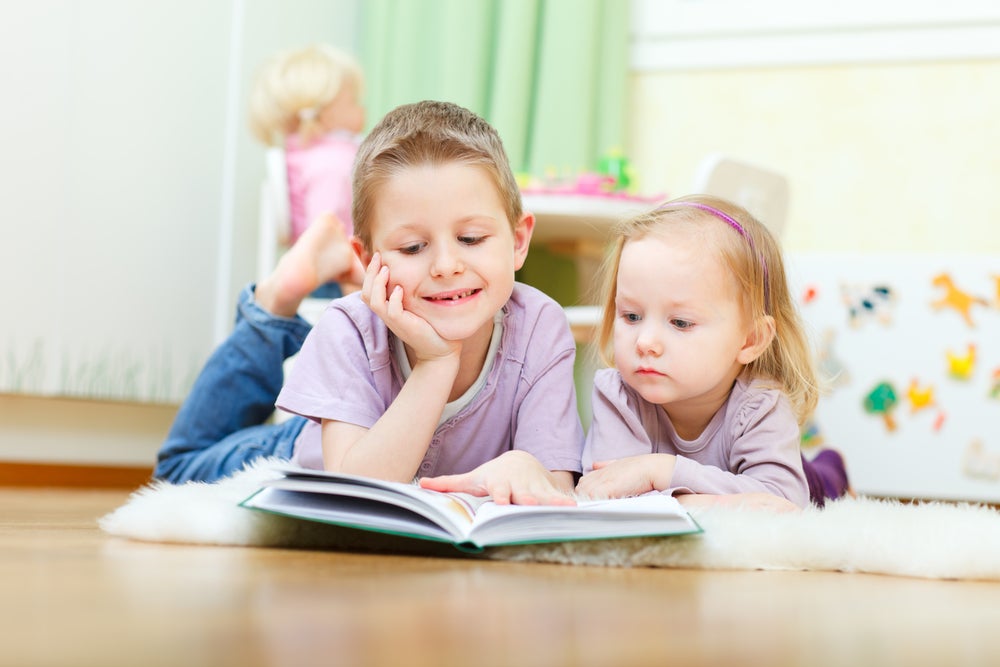 Two children reading from a book