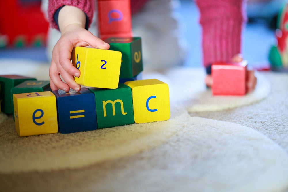 Child playing with blocks reading e=mc2