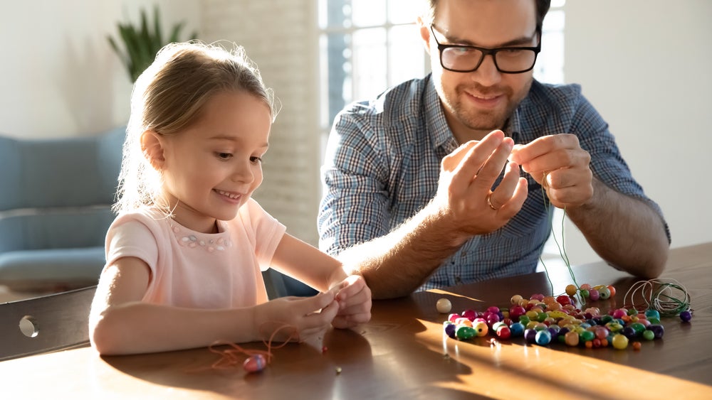 Parent and child making number jewelry together