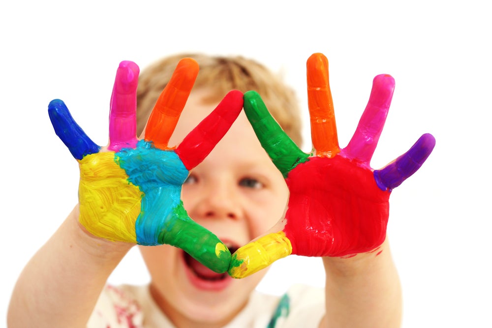 Happy boy showing off hands colored in rainbow paint