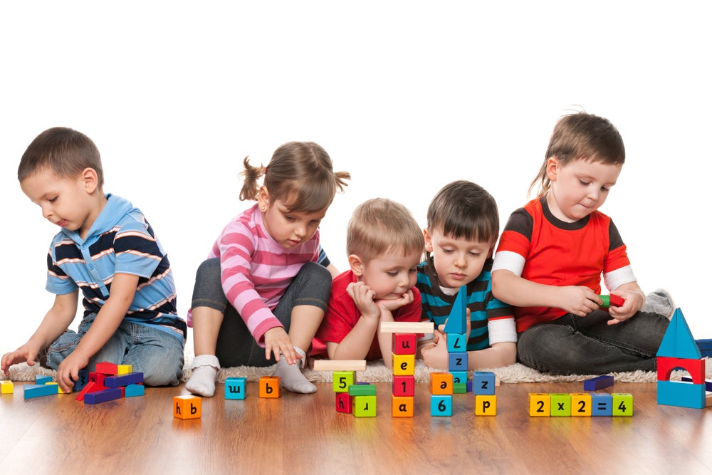Five 4-year-old children playing with blocks together on the floor