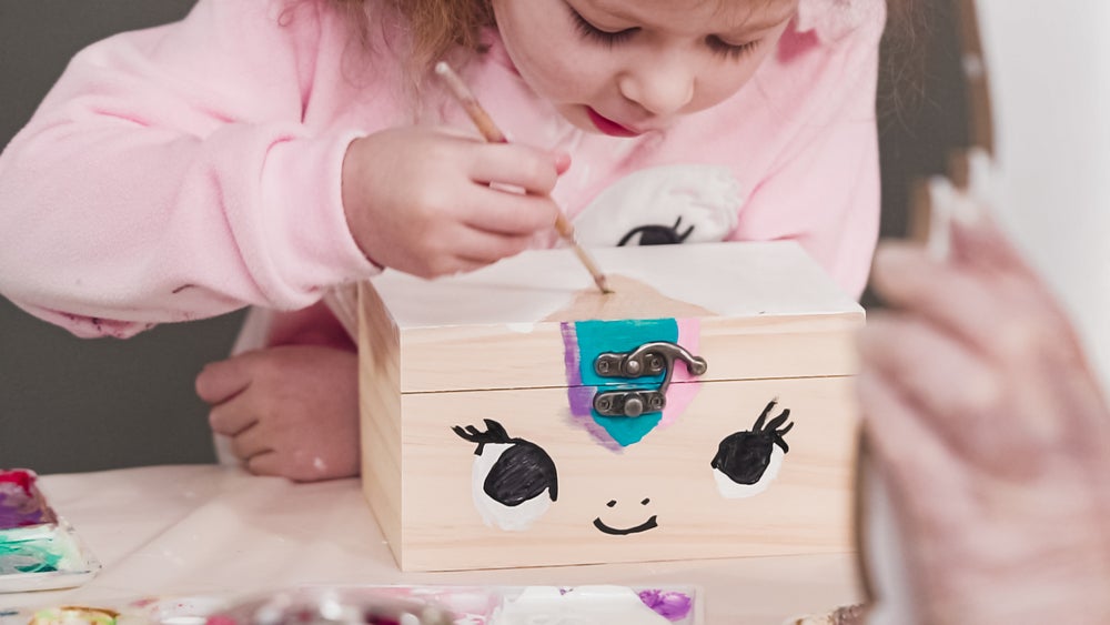 Girl concentrating as she paints a craft box