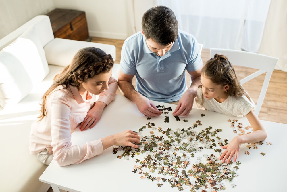 Family doing a puzzle together on a table in the living room
