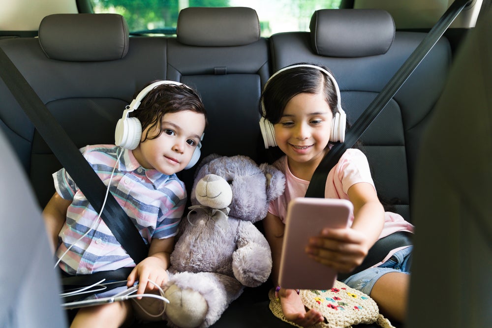 Two kids playing road trip game on phone in car