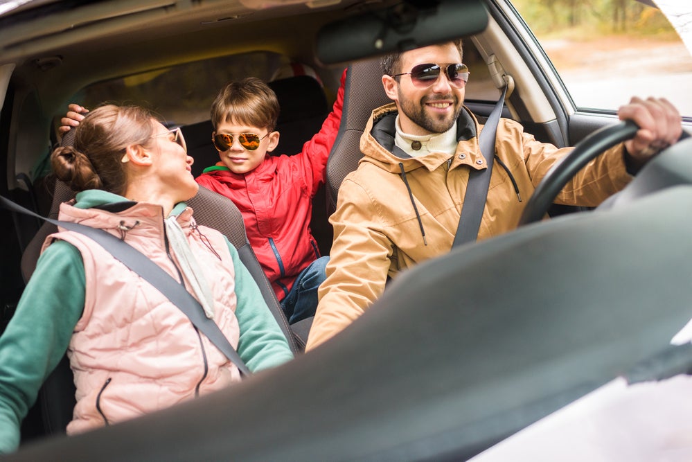Family laughing while playing road trip game in car