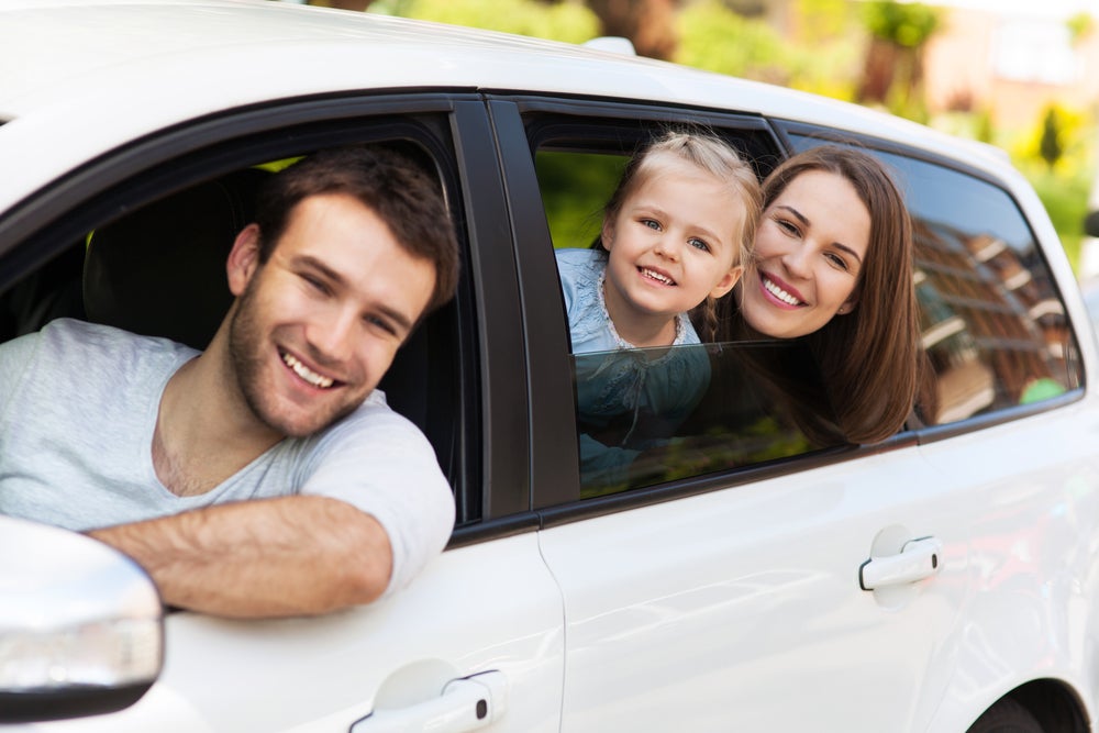 Smiling family leaning out of car windows