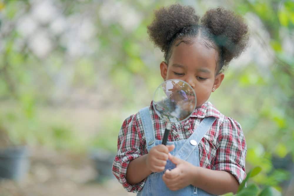 Kid playing with a magnifying glass
