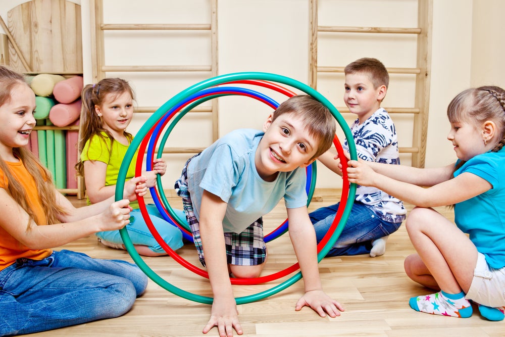 Smiling kid crawling through hula hoops on an indoor obstacle course