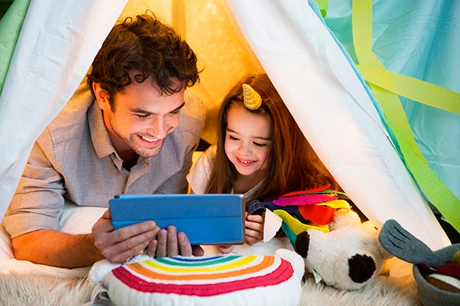 Father and daughter reading together in play tent