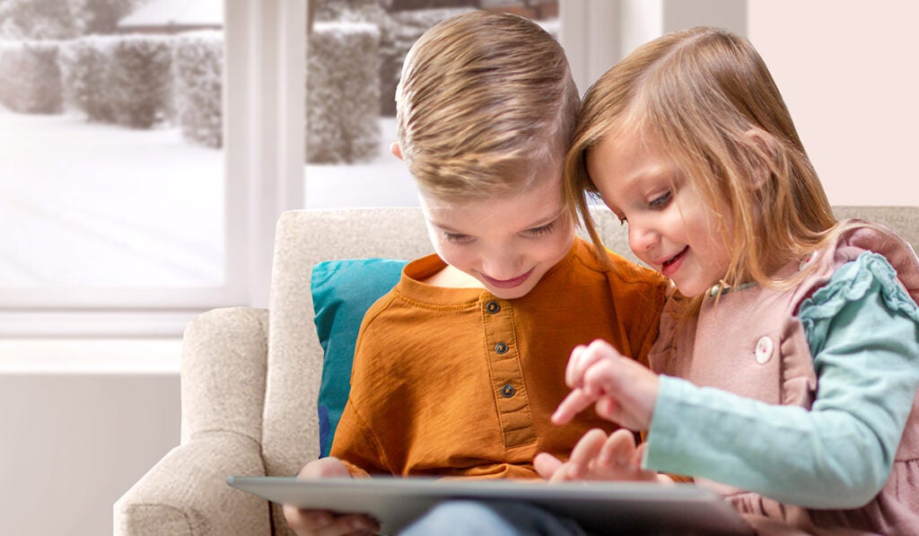 Two kids reading together on a couch