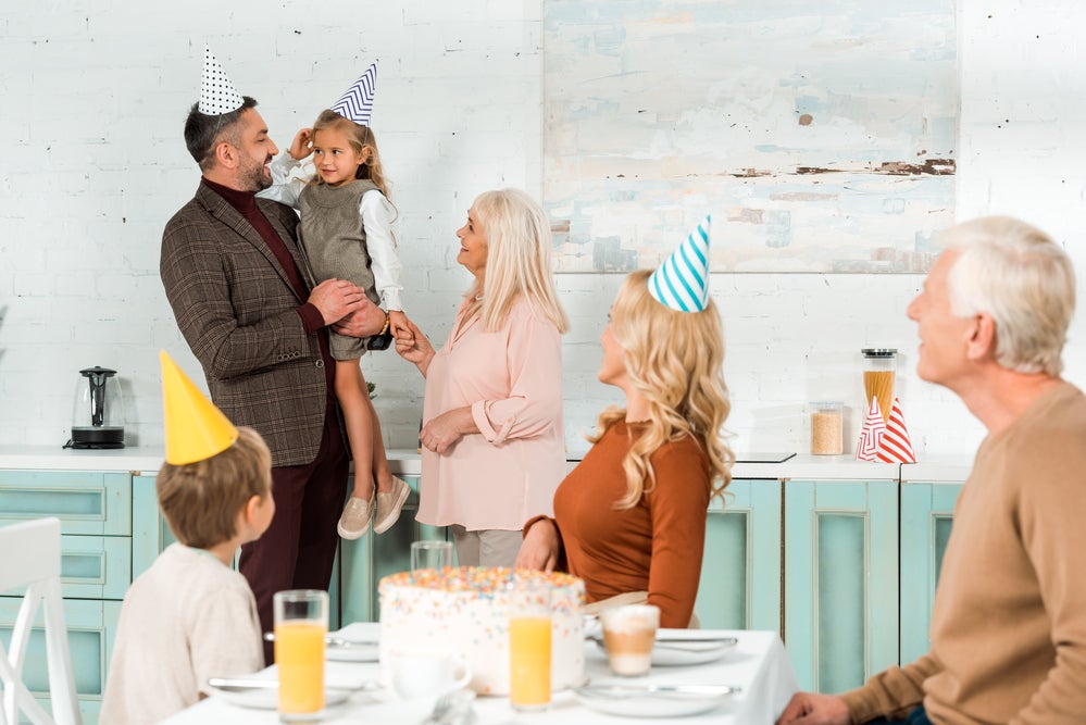 Father holding child in arms at family birthday party