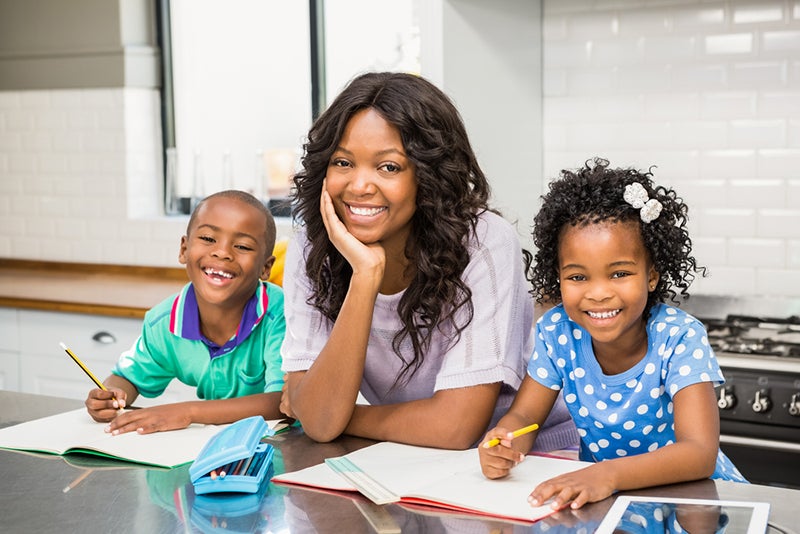 Mother and two kids working on pre-writing activities together in the kitchen