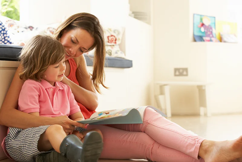 Mother sitting with child reading story indoors