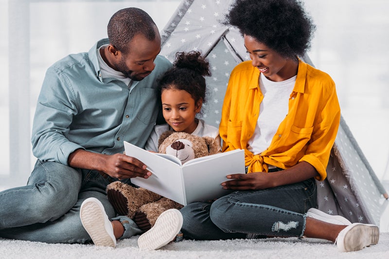 Parents and child reading book together