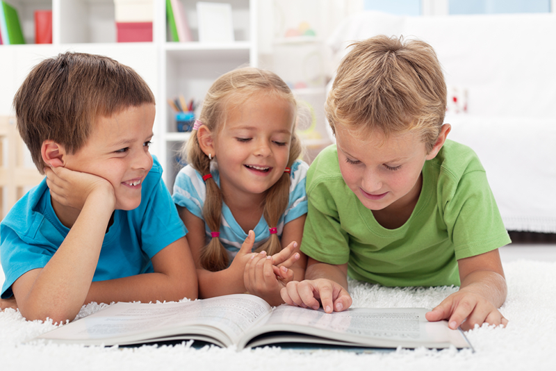 Three kids reading together on the floor