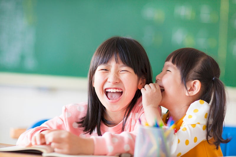 Two kids laughing together in class