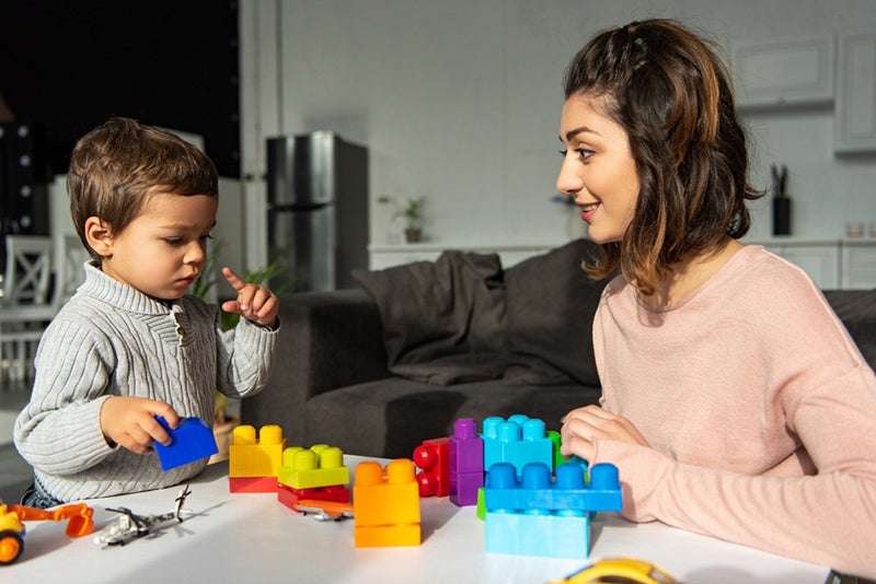 Parent and child playing with brightly colored stackable bricks