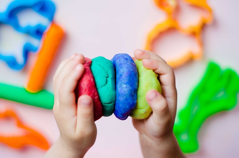 Toddler squishing lumps of colorful play dough together