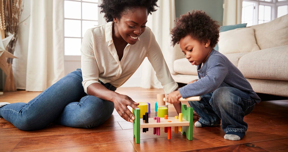 Mother and young son playing with wooden toy at home