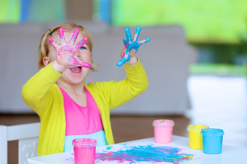 Child with colorful paint all over their hands