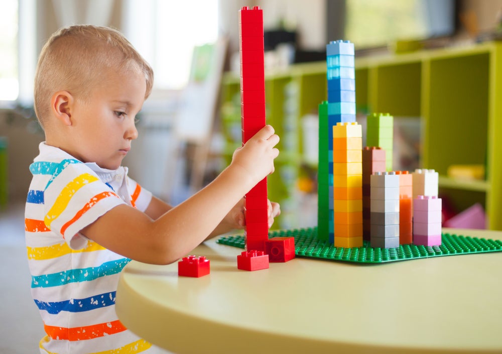 Child playing with building bricks in preschool