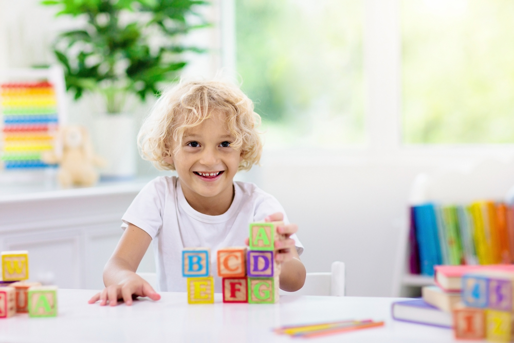 Smiling child playing with alphabet blocks