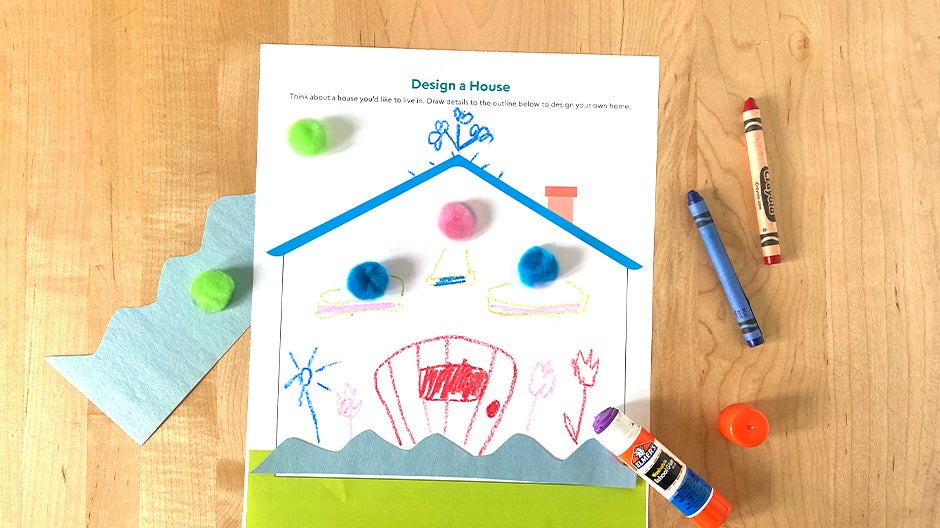 Completed Design a House printable on table with crayons, glue stick, pom-poms, and paper crown