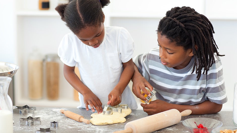 Kids cutting out cookies on a counter