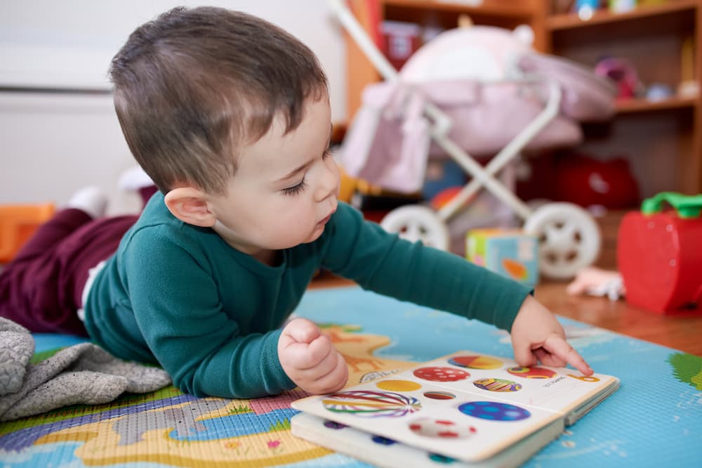 Boy pointing at letters in a book on playroom floor