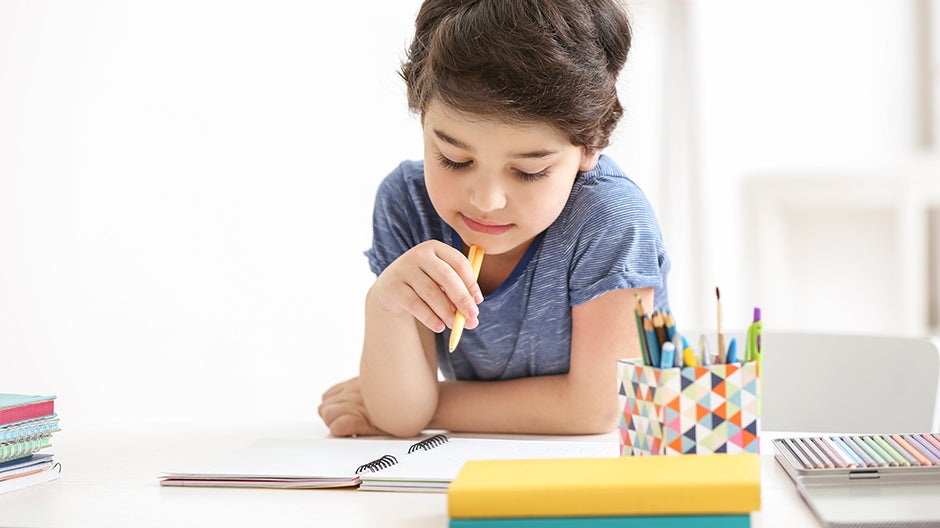 Child holding pencil and thinking while looking at notebook