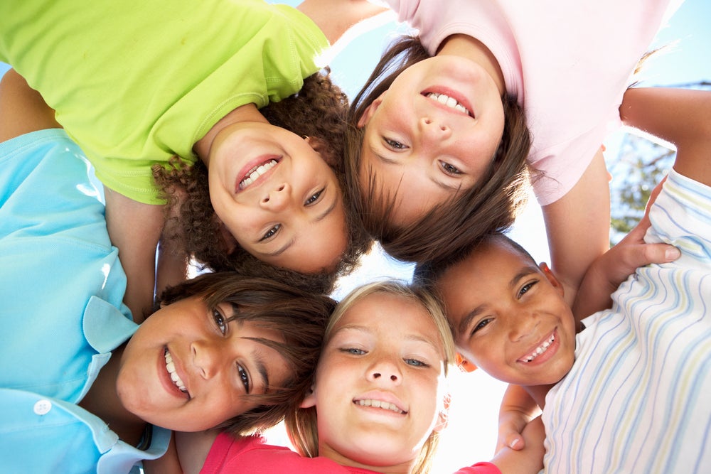 Kids in a circle with their heads together looking down