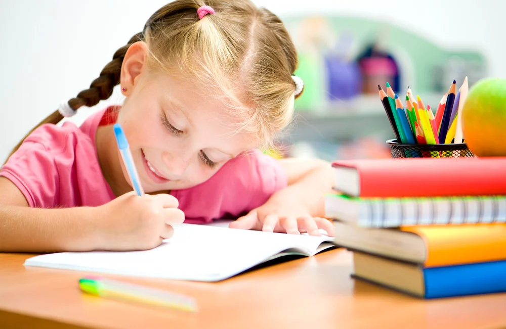 Child writing in an open journal on a table