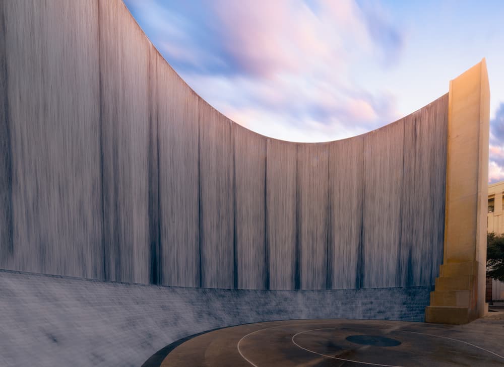 The Gerald D. Hines water wall sculpture in Houston: a long, curved stone wall at sunset