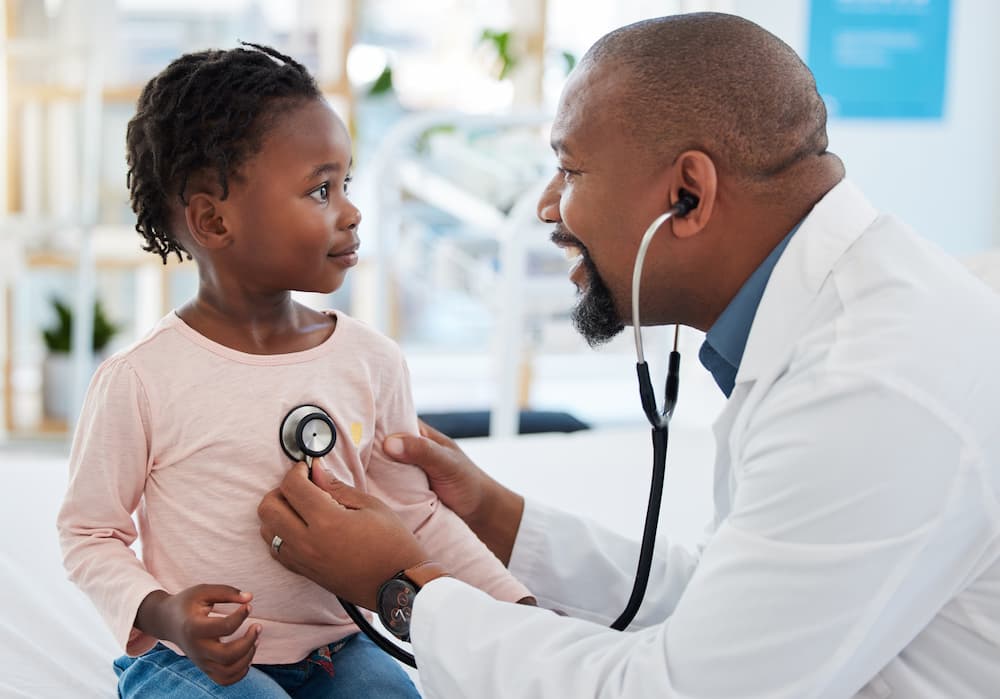 Pediatrician checking toddler's heartbeat with stethoscope