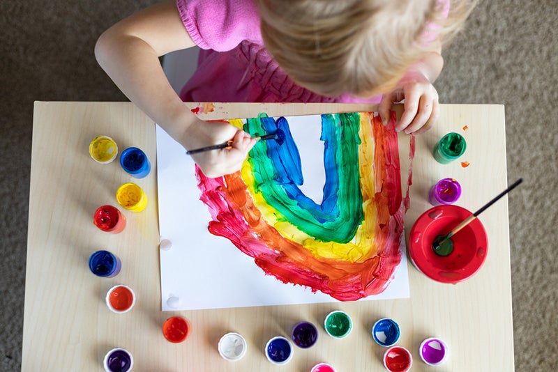 Child painting a rainbow for an indoor art show