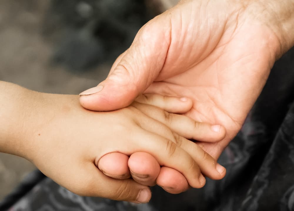 Adult holding a child's hand to show kindness