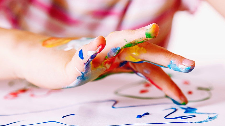 Preschooler finger painting with vibrant colors on a large canvas
