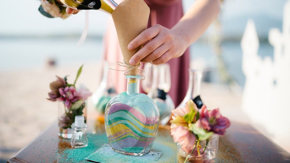 Colorful layers of sand being poured for a sensory bottle