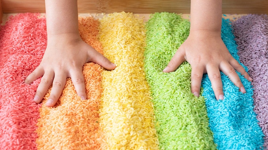 Colorful rainbow rice in a sensory bin for engaging tactile and visual kids' play.