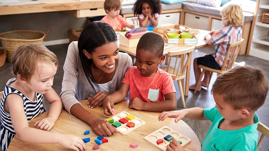 Teacher working with students on early childhood education in a preschool classroom