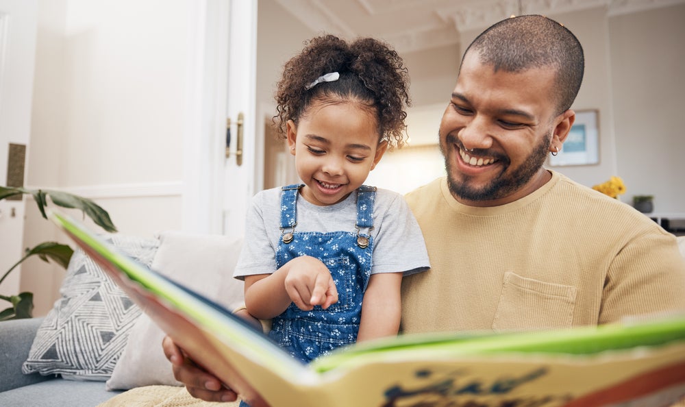Dad, daughter and book on sofa together