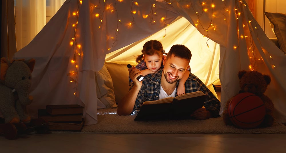 Dad reading with daughter in a tent