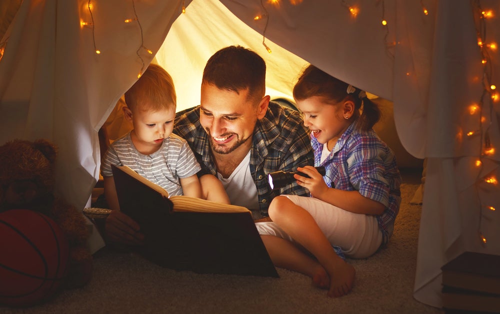 father reading with his children in a tent