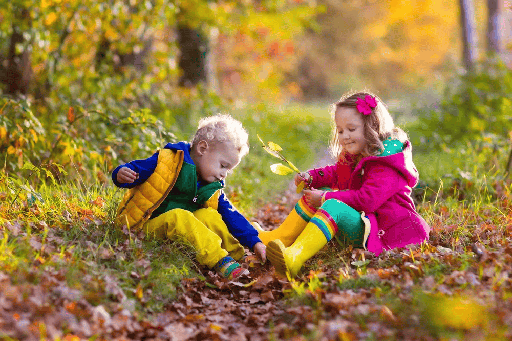 two kids playing outside in the leaves