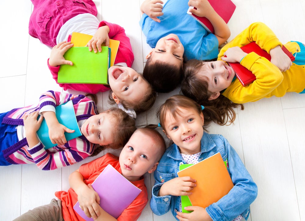 toddlers laying in a circle holding books