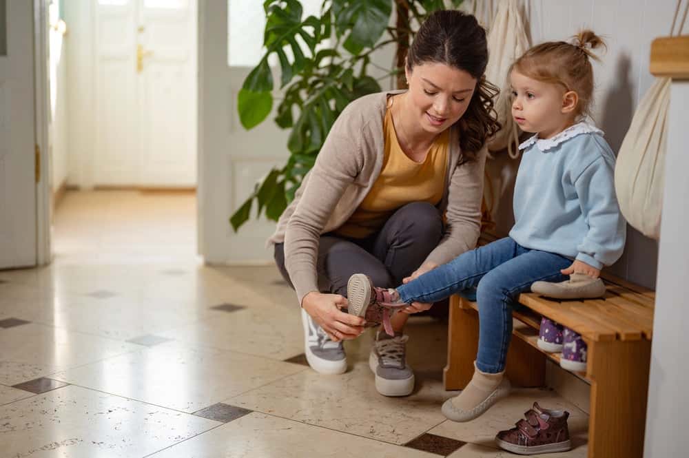 Mom putting on kids shoe for her morning routine